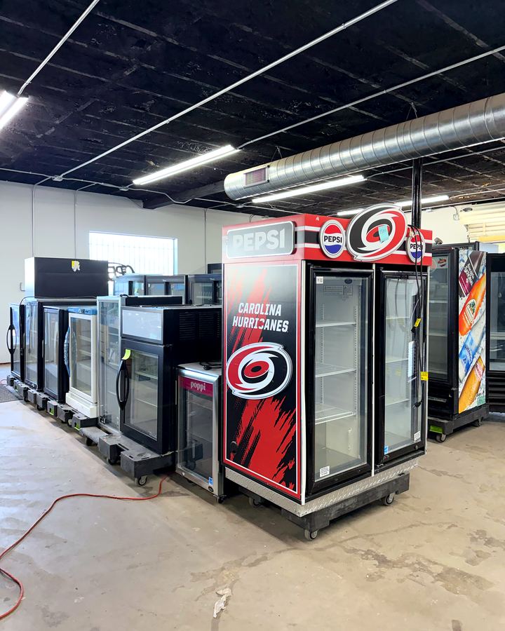 Rows of glass door coolers and freezers on the Efficient Equipment showroom floor.
