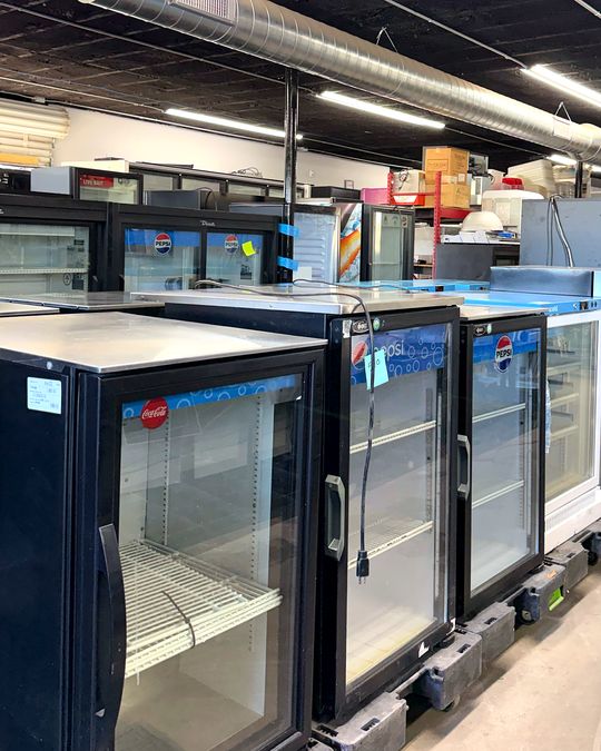 A row of black back-bar glass door coolers on the showroom floor.