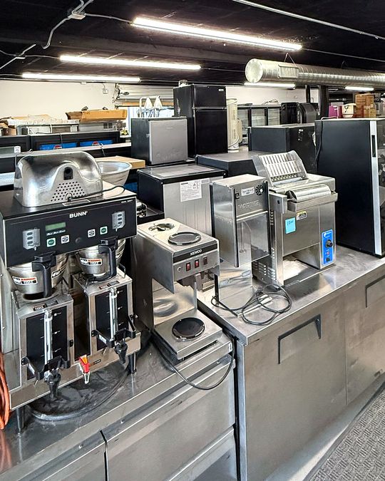A stainless prep line with commercial coffee brewers and kitchen equipment.